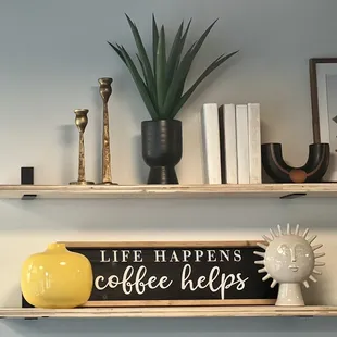 a shelf with coffee cups and a sign that says life happens coffee helps