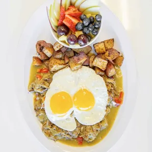 Huevos Verdes -chile verde pork topped with two over easy eggs, house potatoes, and side of seasonal fruit