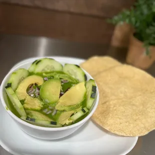 a bowl of cucumber and a tortilla