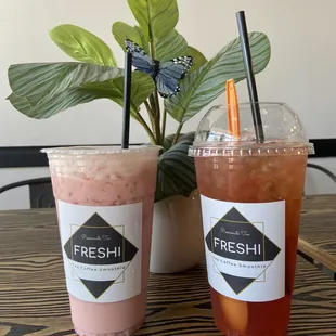two drinks sitting on a table next to a potted plant
