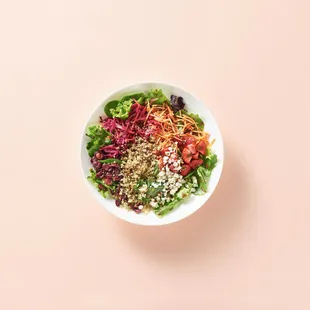 a bowl of salad on a pink background
