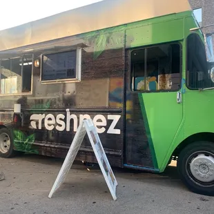a green food truck parked in a parking lot