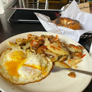Over medium egg, potatoes and bagel