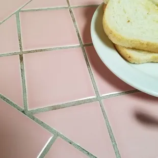 a plate of toast on a pink tile floor