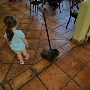 Dustpan in the middle of the walkway during dining hours.