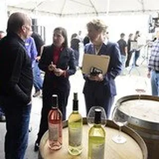 a group of people standing around a barrel of wine