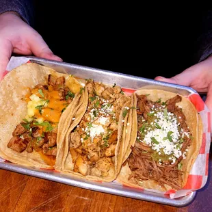 a person holding a tray of tacos