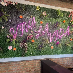 a wall of flowers and plants with the word hello written on it