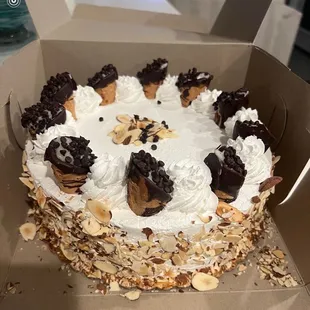 Cassada Cake. 3 layers of yellow cake soaked with Rum, cannoli filling, whipped cream icing, cannolis on top and almonds on the side.