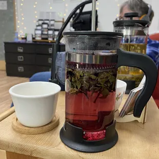 In the shop, they serve your tea in a french press, and you can see some of the displays and fairy lights in the background.