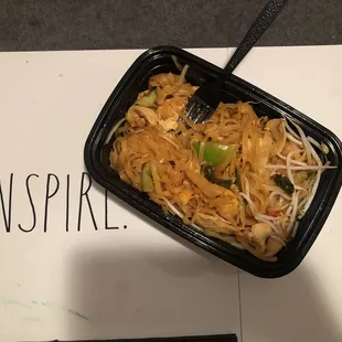 a black container with noodles and chopsticks