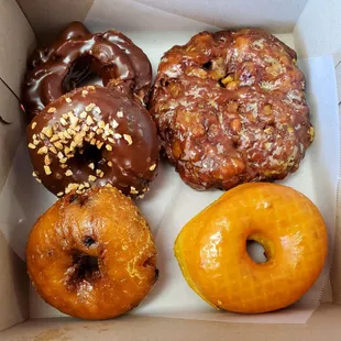 Clockwise from 12 o'clock: apple fritter, glazed, blueberry cake, chocolate cake w/ peanuts, chocolate old-fashioned
