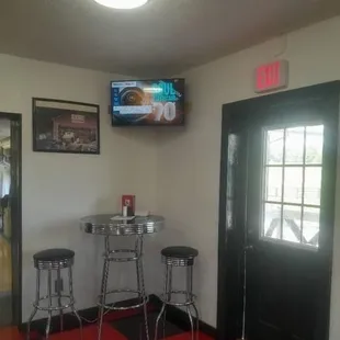 a bar with two stools and a television