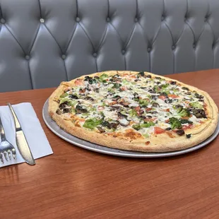 a pizza on a table with a fork and knife