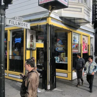 people walking on the sidewalk in front of a liquor store