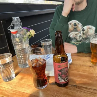 a man sitting at a table with a bottle of beer