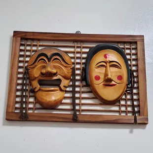 two wooden masks hanging on a wall
