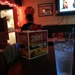 a person sitting at a table with a drink and a box of 2xoxite