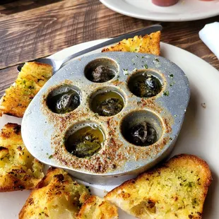 a muffin pan with olives and bread