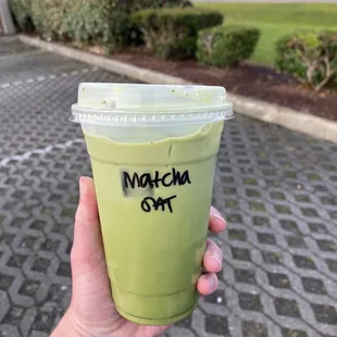a hand holding a cup of matcha green tea