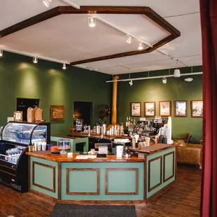 a coffee shop with green walls and wood floors