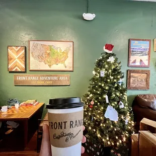 a person holding a coffee cup in front of a christmas tree
