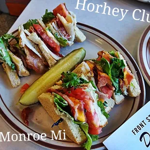 two plates of sandwiches and a pickle