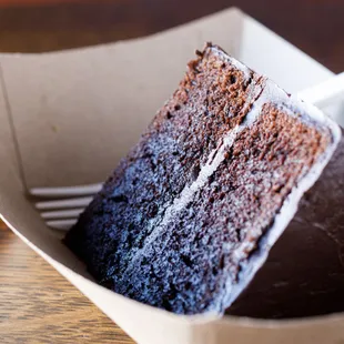 a slice of chocolate cake in a paper container