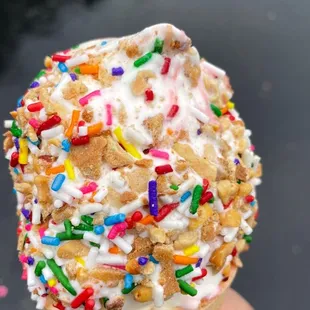 a hand holding an ice cream cone with sprinkles