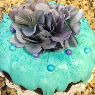 a cake with blue icing and purple flowers