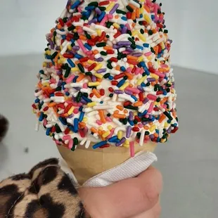 a person holding an ice cream cone with sprinkles