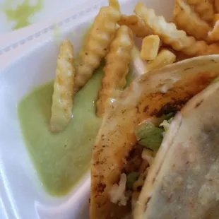 a taco and fries in a styrofoam container
