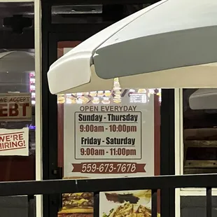 posted hours, dark building. photo taken at 21:30