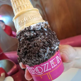 a hand holding a chocolate ice cream cone