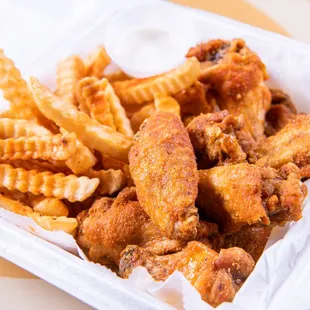 chicken wings and fries in a styrofoam container