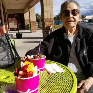 a woman sitting at a table with a bowl of fruit