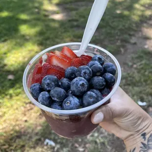 a hand holding a cup of fruit