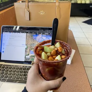 a person holding a bowl of food in front of a laptop