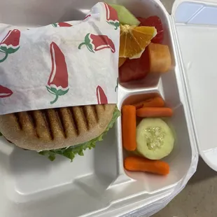Chicken breast sandwich on sourdough bread and fruit