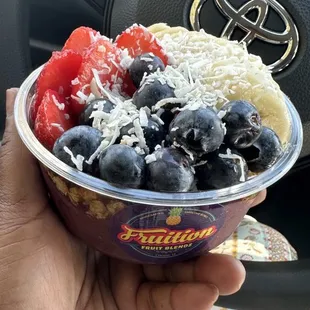 a hand holding a bowl of fruit