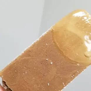 a hand holding a popsicle covered in peanut butter