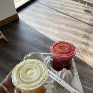  a hand holding a plastic container with two different drinks