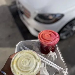  a person holding a plastic container with two drinks