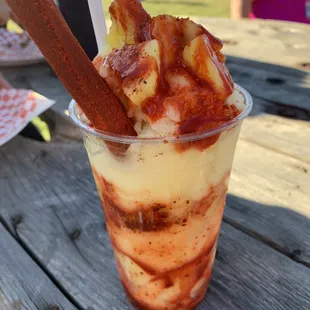a dessert in a plastic cup on a picnic table