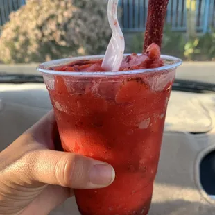 a hand holding a plastic cup with a straw sticking out of it