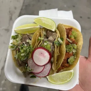 a hand holding a plate of tacos