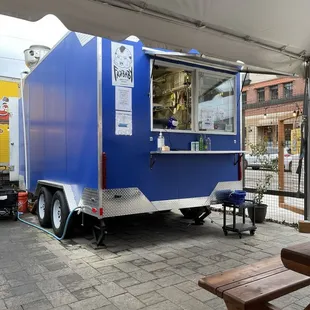 a blue food truck parked under a tent