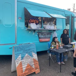 people sitting at a table in front of a food truck