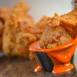 a hand dipping a piece of fried chicken