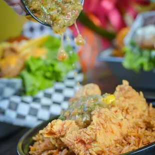 a person pouring sauce over a bowl of food